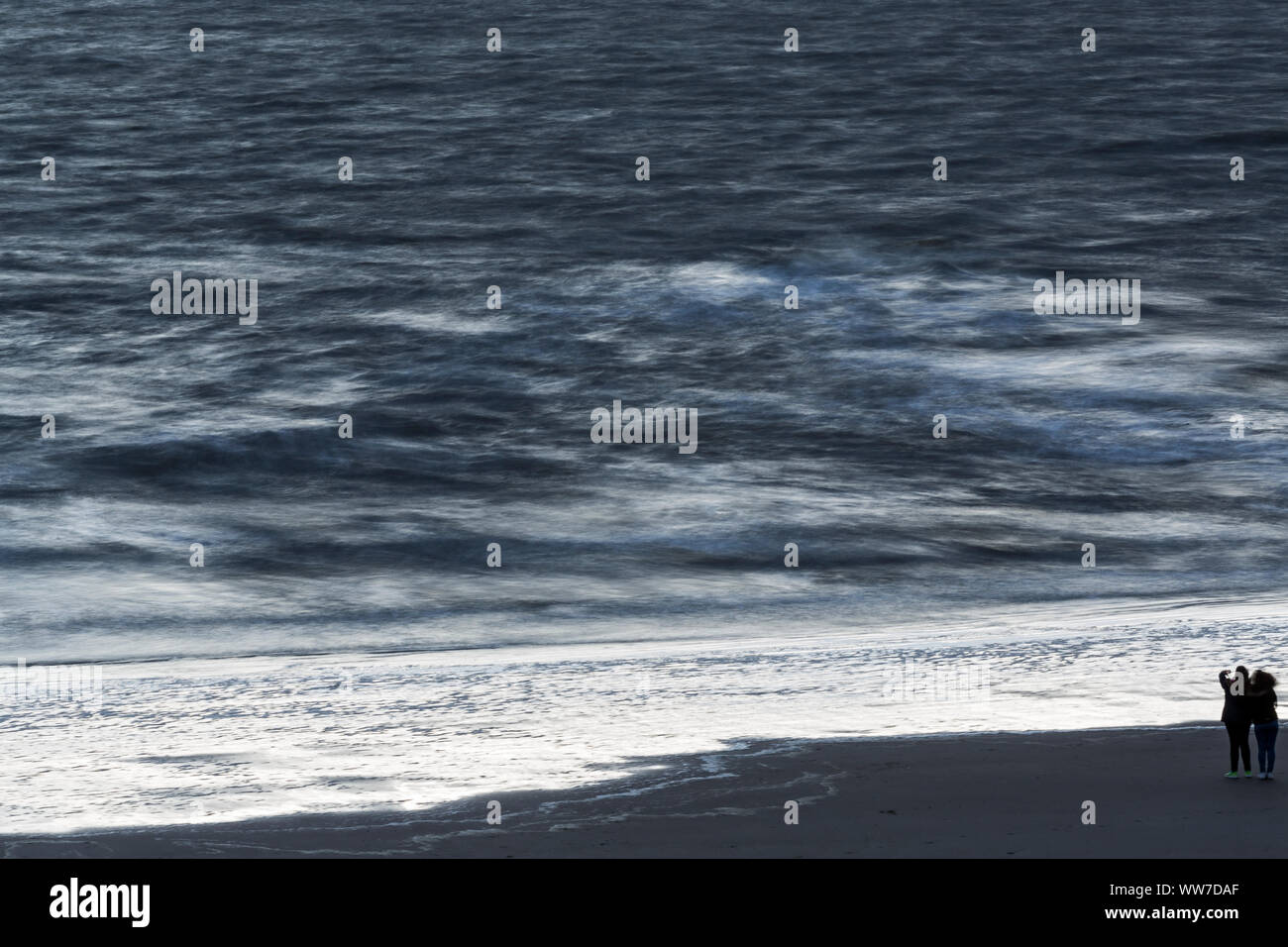 Norderney, Weststrand, Strand, zwei junge Frauen, Meer, Wellen, Bewegung, blaue Stunde, Langzeitbelichtung Stock Photo