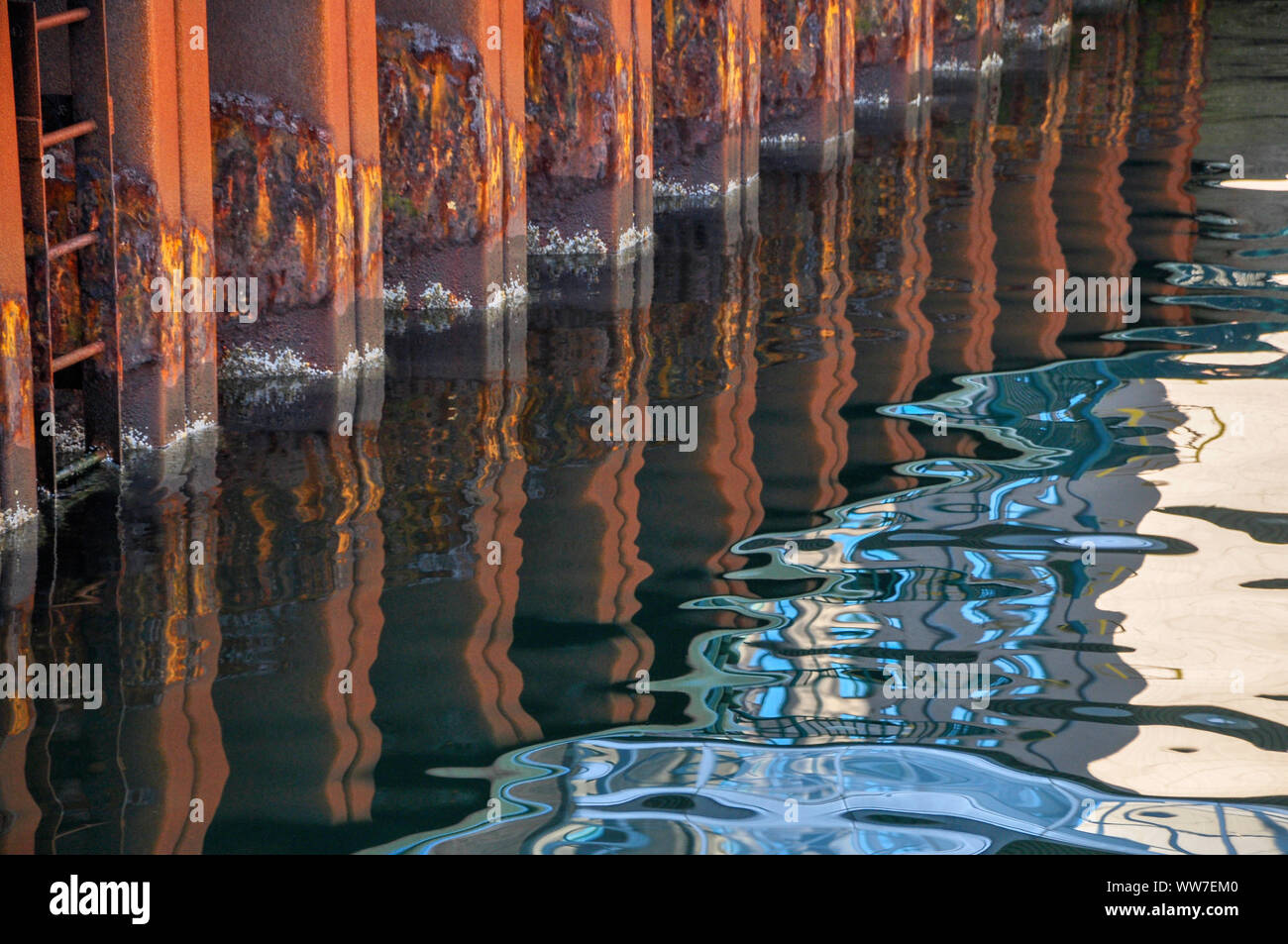 Bold abstract image of a rusting seawall and reflection in the water. Stock Photo