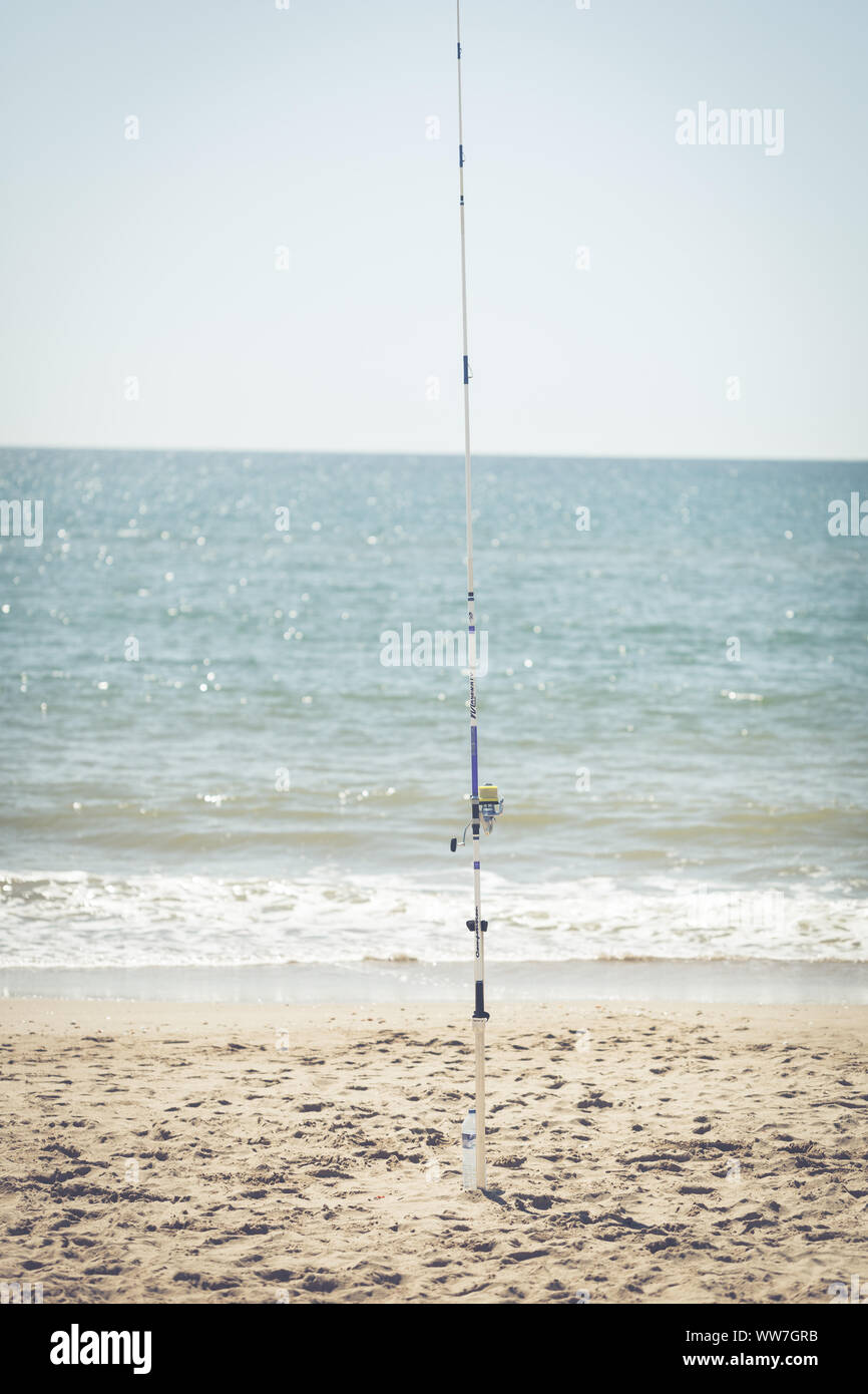A fishing rod sticking in the sand at the sea, view and recreation on ...