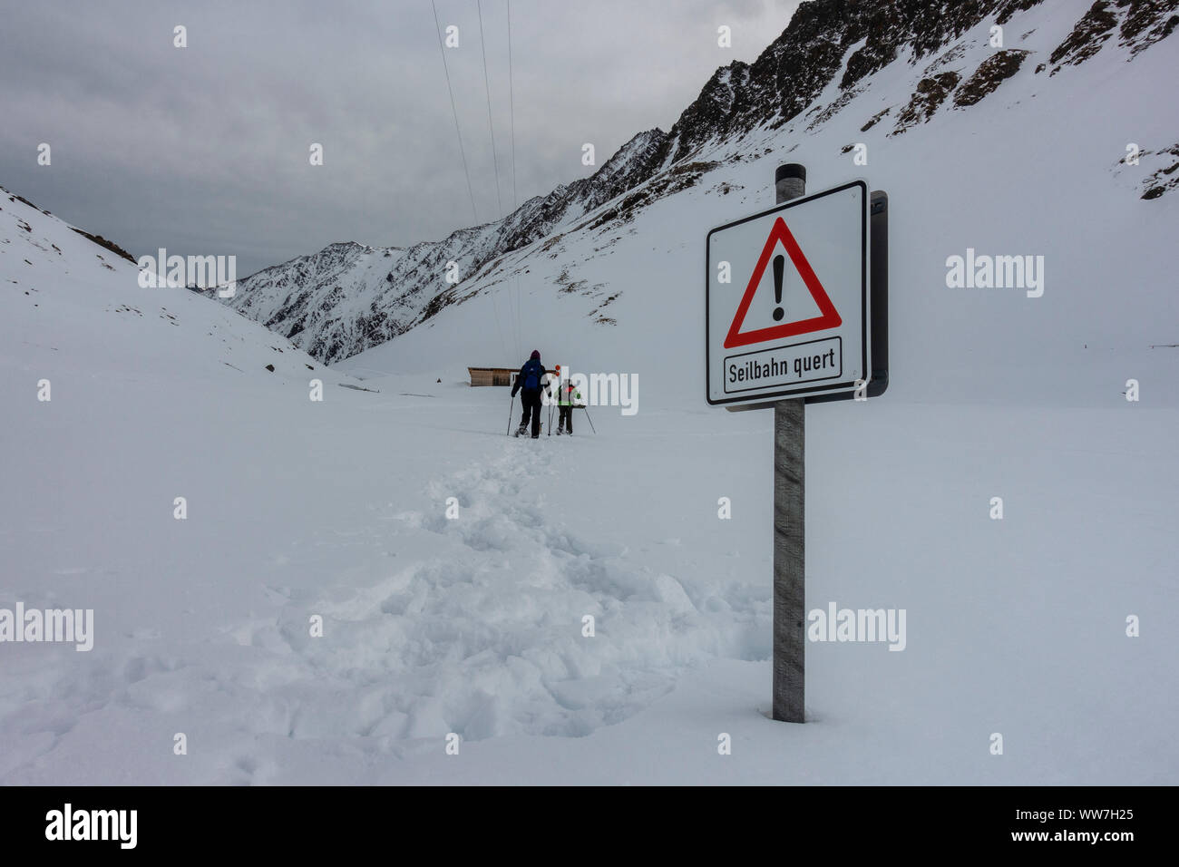 Austria, Tyrol, St. Sigmund im Sellrain, snowshoe hikers crossing under the goods cable lift of the Pforzheimer HÃ¼tte Stock Photo