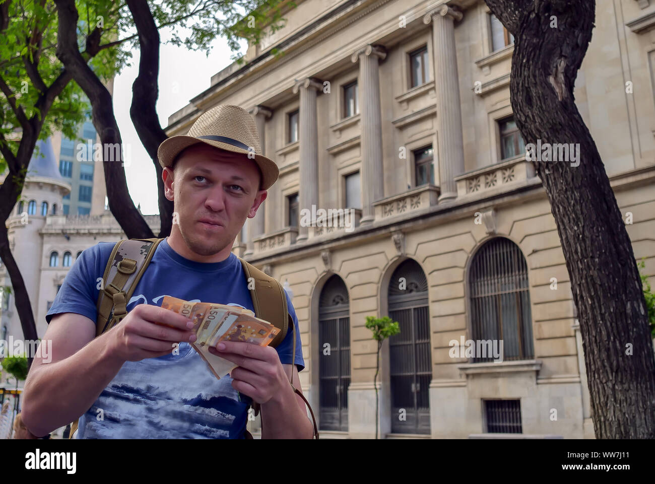 Young man tourist counts money standing on the street Stock Photo