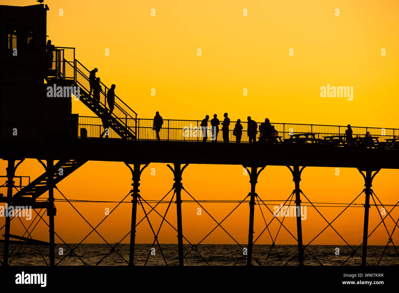 Aberystwyth Wales UK, Friday 13 September 2019 People standing on Aberystwyth’s Victorian seaside pier are silhouetted as they watch the last rays of the suns as it sets over Cardigan Bay, on a glorious early autumn evening, The weekend is expected to be warm and settled with temperatures in the mid 20’s Celsius in parts of the south east of the UK  Photo credit Keith Morris/Alamy Live News Stock Photo