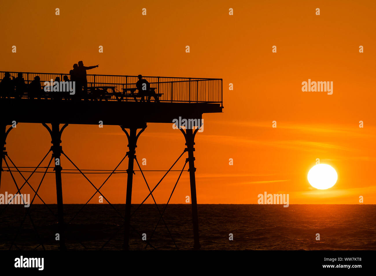 Aberystwyth Wales UK, Friday 13 September 2019 People standing on Aberystwyth’s Victorian seaside pier are silhouetted as they watch the last rays of the suns as it sets over Cardigan Bay, on a glorious early autumn evening, The weekend is expected to be warm and settled with temperatures in the mid 20’s Celsius in parts of the south east of the UK  Photo credit Keith Morris/Alamy Live News Stock Photo