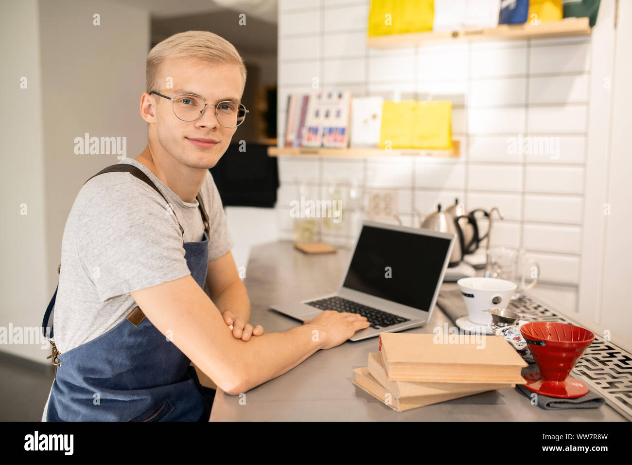 Happy young man in uniform and eyeglasses learning in front of laptop Stock Photo
