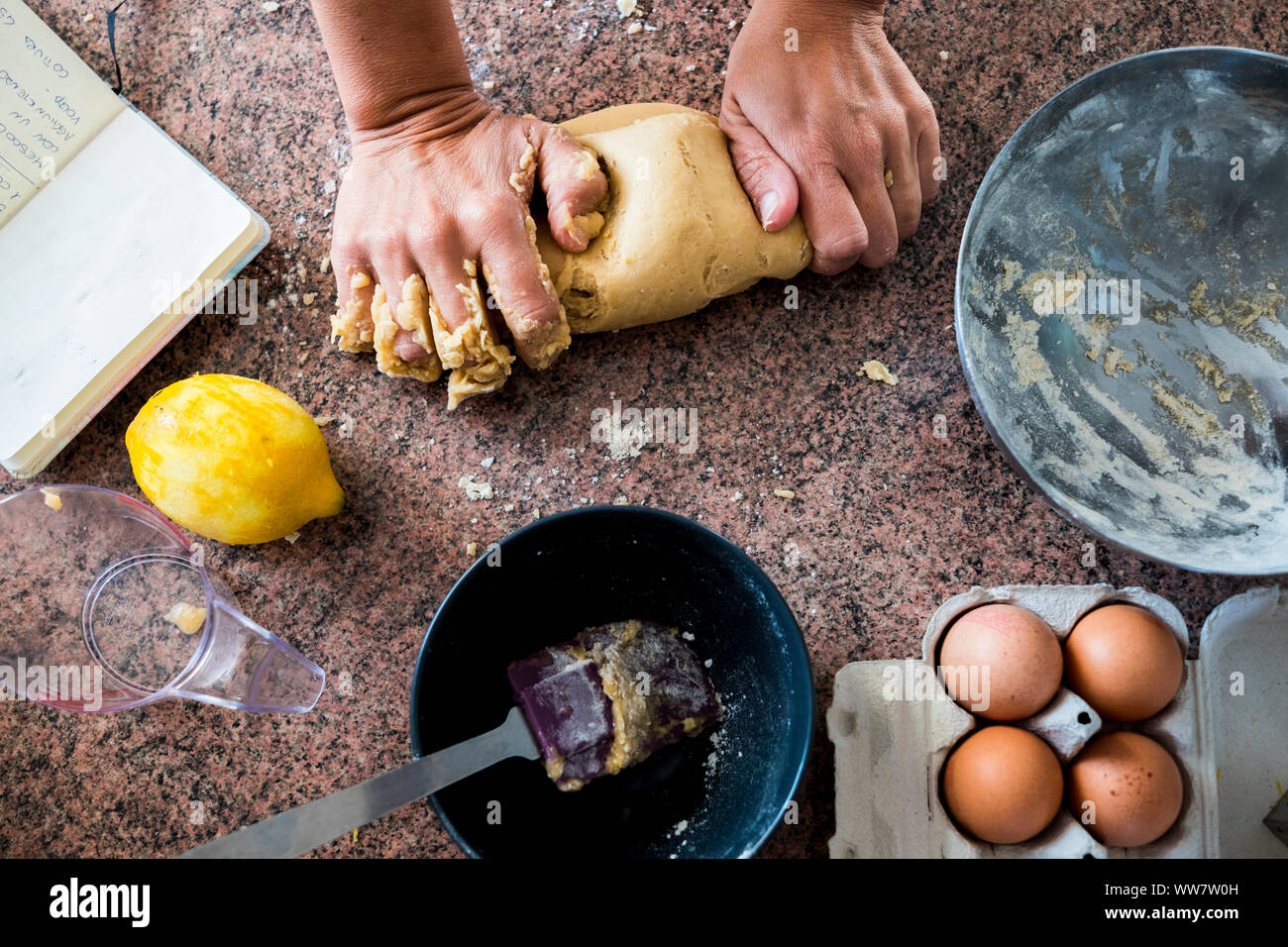A pair of woman strong hands doing pasta for a cake in the kitchen. Eggs and limon. Taken from above with different point of view Stock Photo