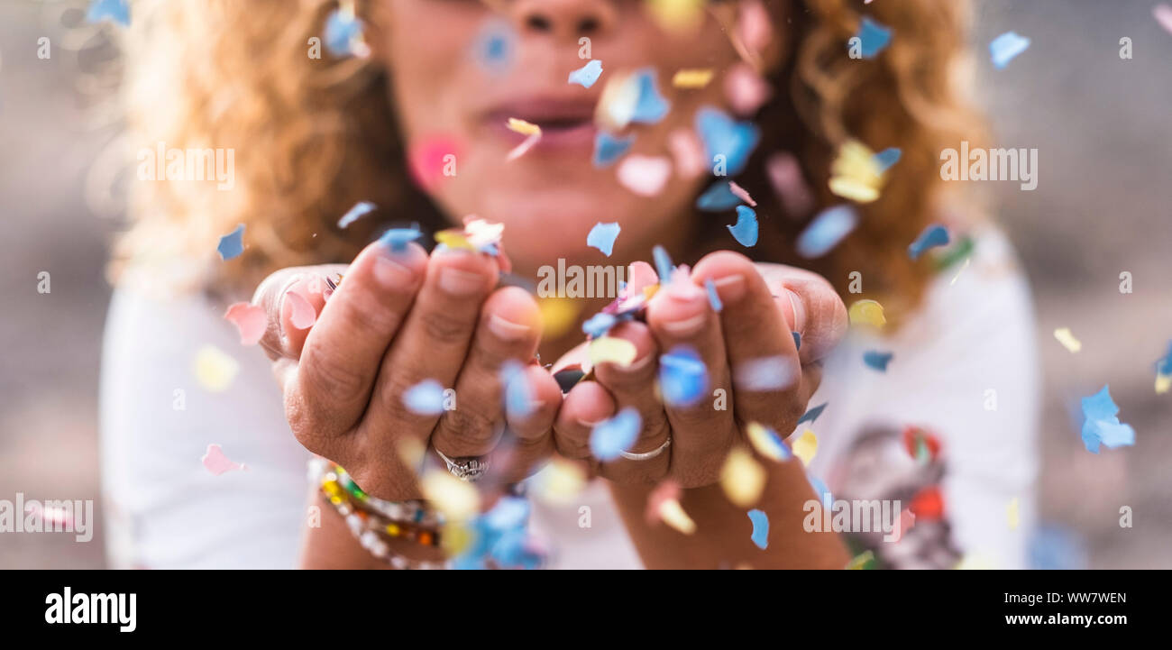 beautiful defocused woman blow confetti from hands. celebration and event concept. happiness and coloured image. movement and ahppiness having fun Stock Photo
