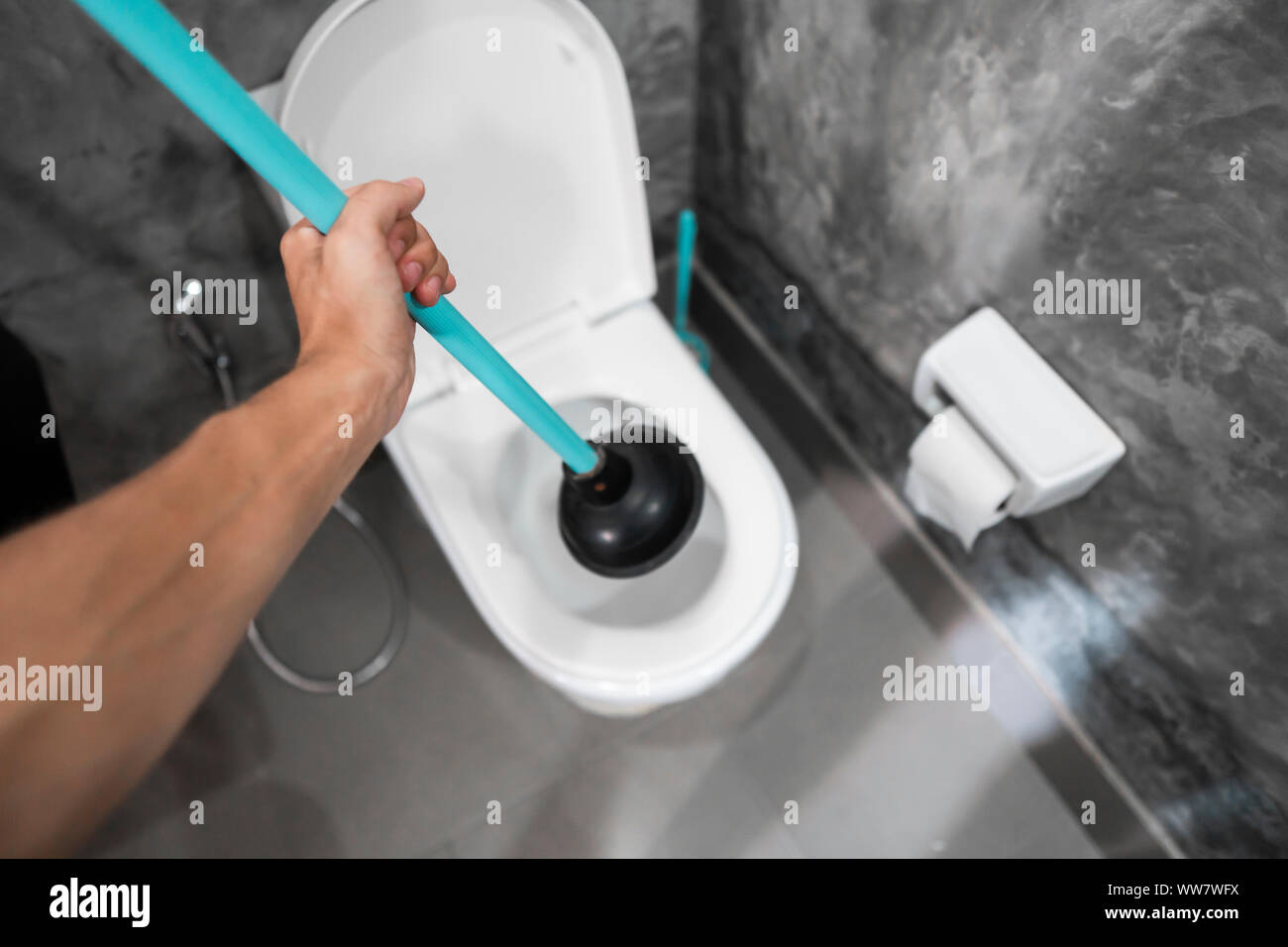 Toilet repair by hand with a Toilet Plunger. Plumbing. A plumber uses a plunger to unclog a toilet. Toilet Plunger. Stock Photo