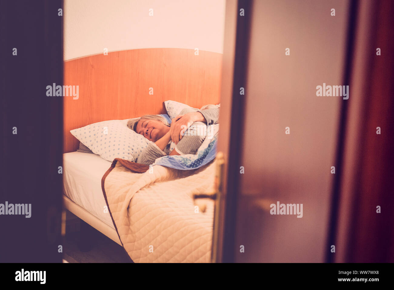 adult aged couple sleep at the bedroom at home, indoor daily scene for sweet love forever. retro look filter. hidden scene. sweetness and elderly Stock Photo