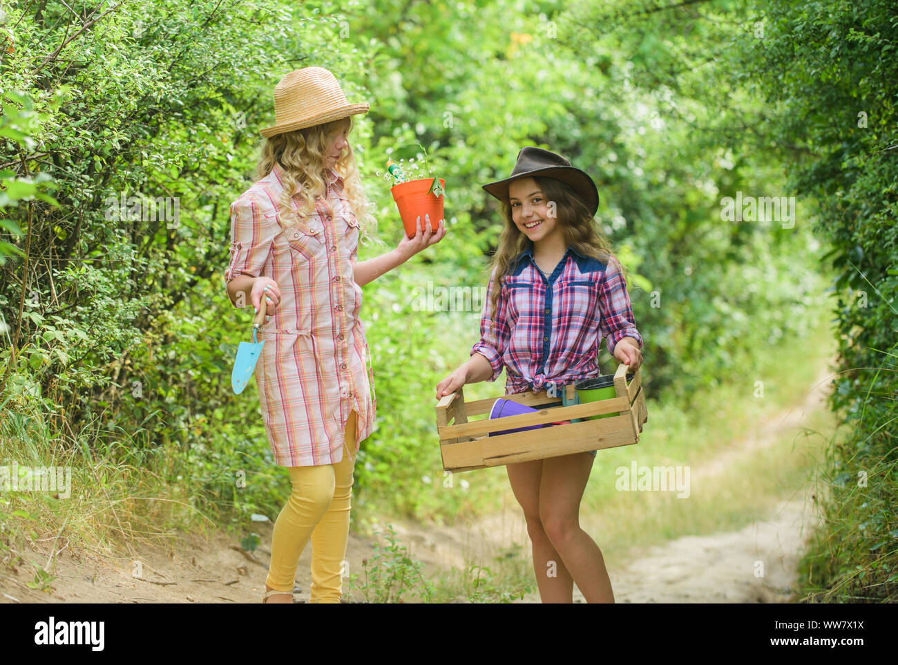 Flowers need our care. small girls farmer in village. happy farming. spring country side. earth day. summer family farm. protect nature. Rich harvest. children work using gardening tool. Stock Photo