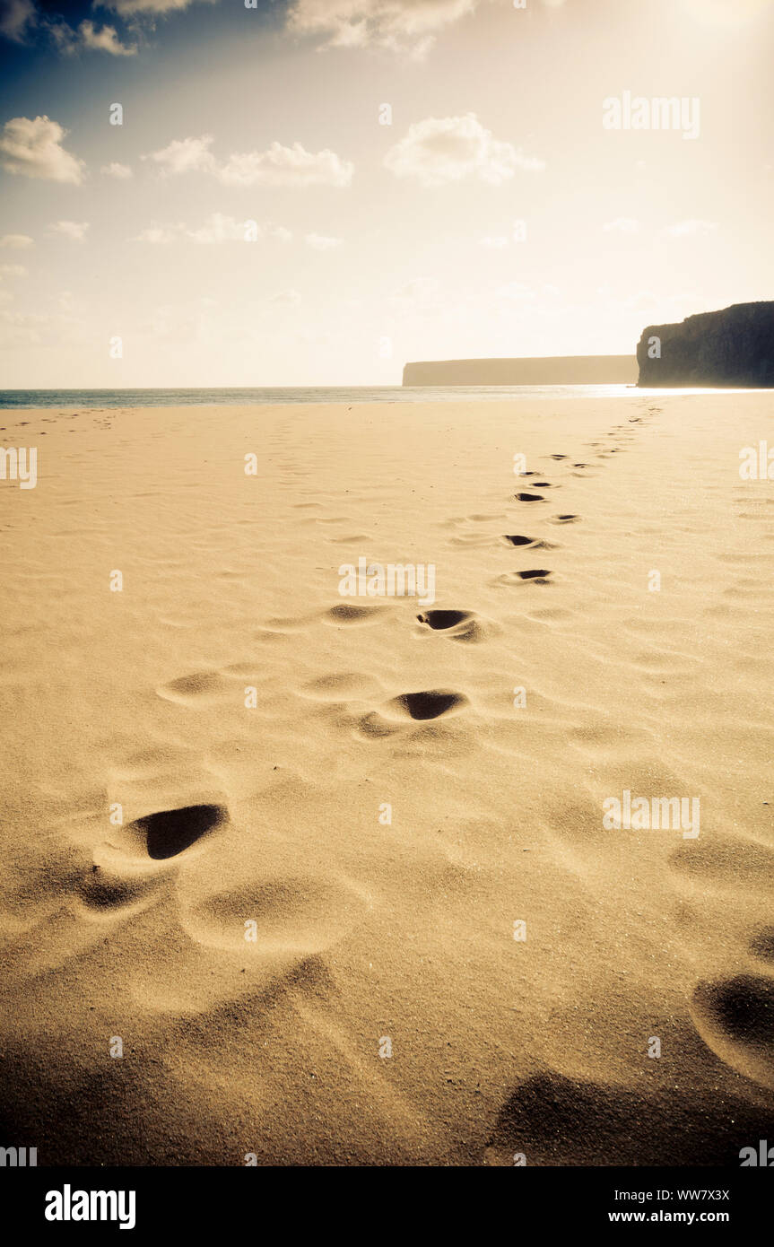 infinite beach in portugal with yellow sand and footprint. mountains and rocks. travel and vacation concept with no tourists and tourism Stock Photo
