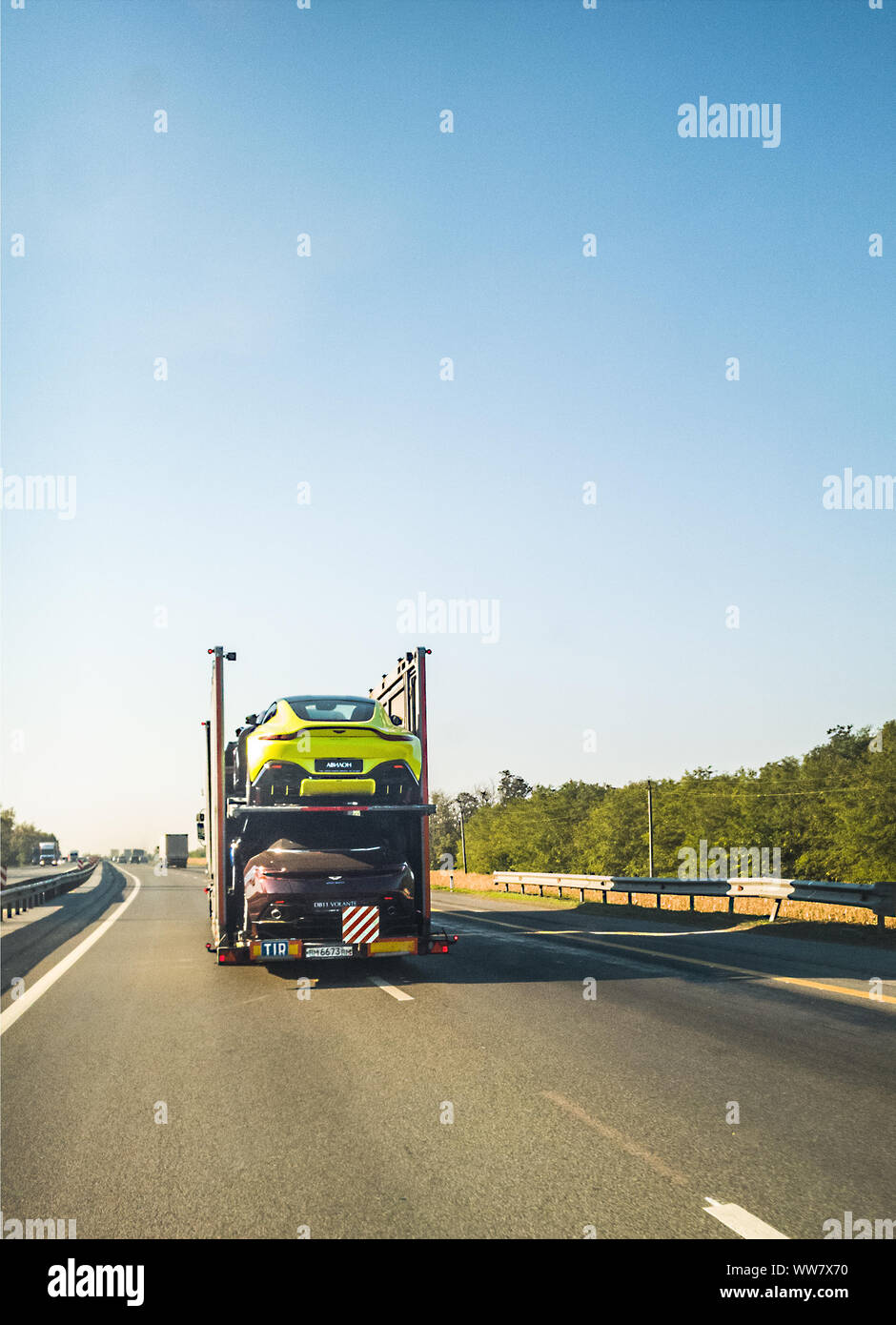 2018: rack-truck moves along scenic highway laden with Aston Martin sportcars Stock Photo