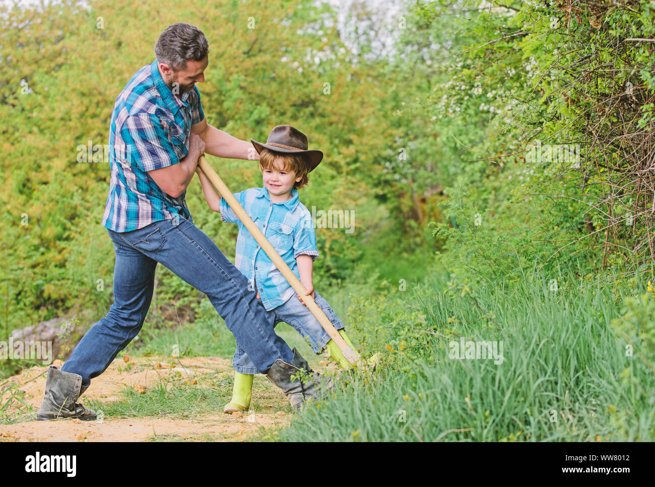 father and son digging ground in forest with shovels, ecology