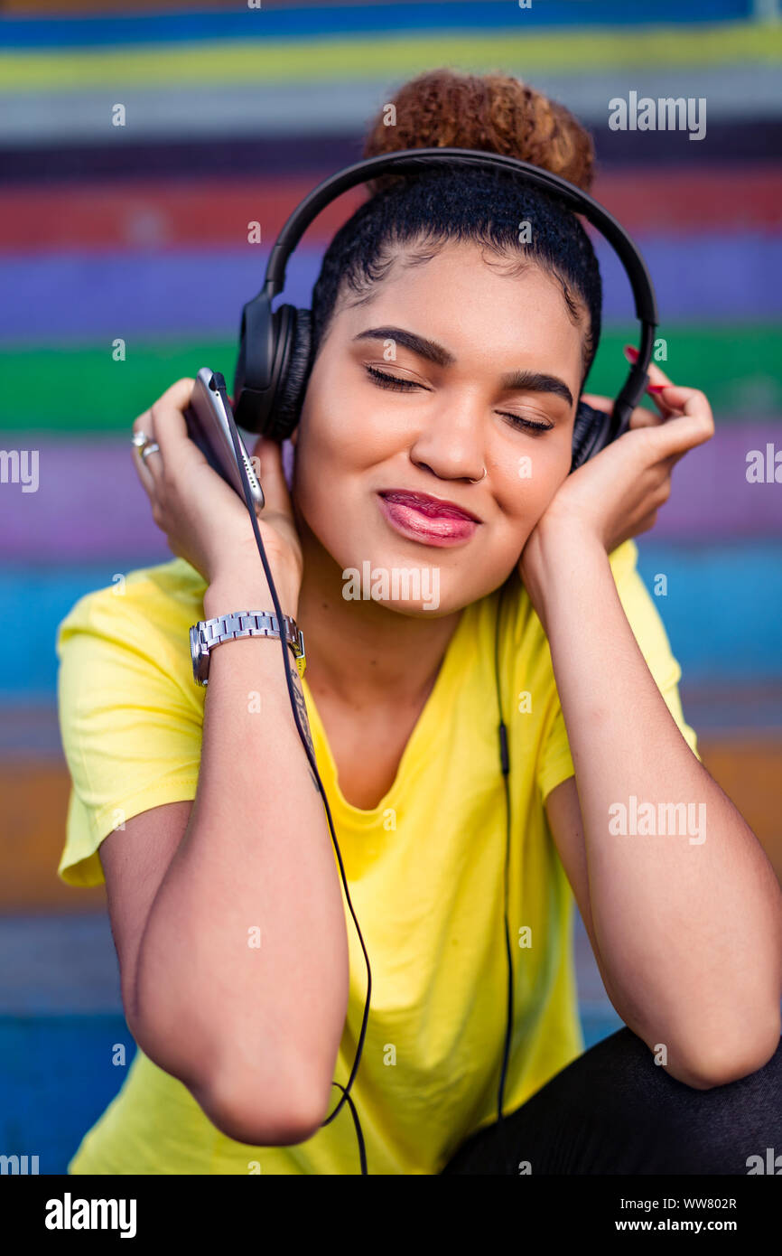 Pretty young black african american woman listening to music with a ...