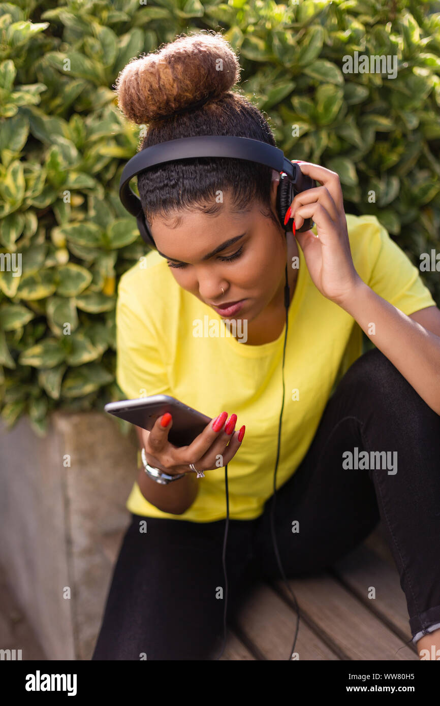 Pretty young black african american woman listening to music with a ...