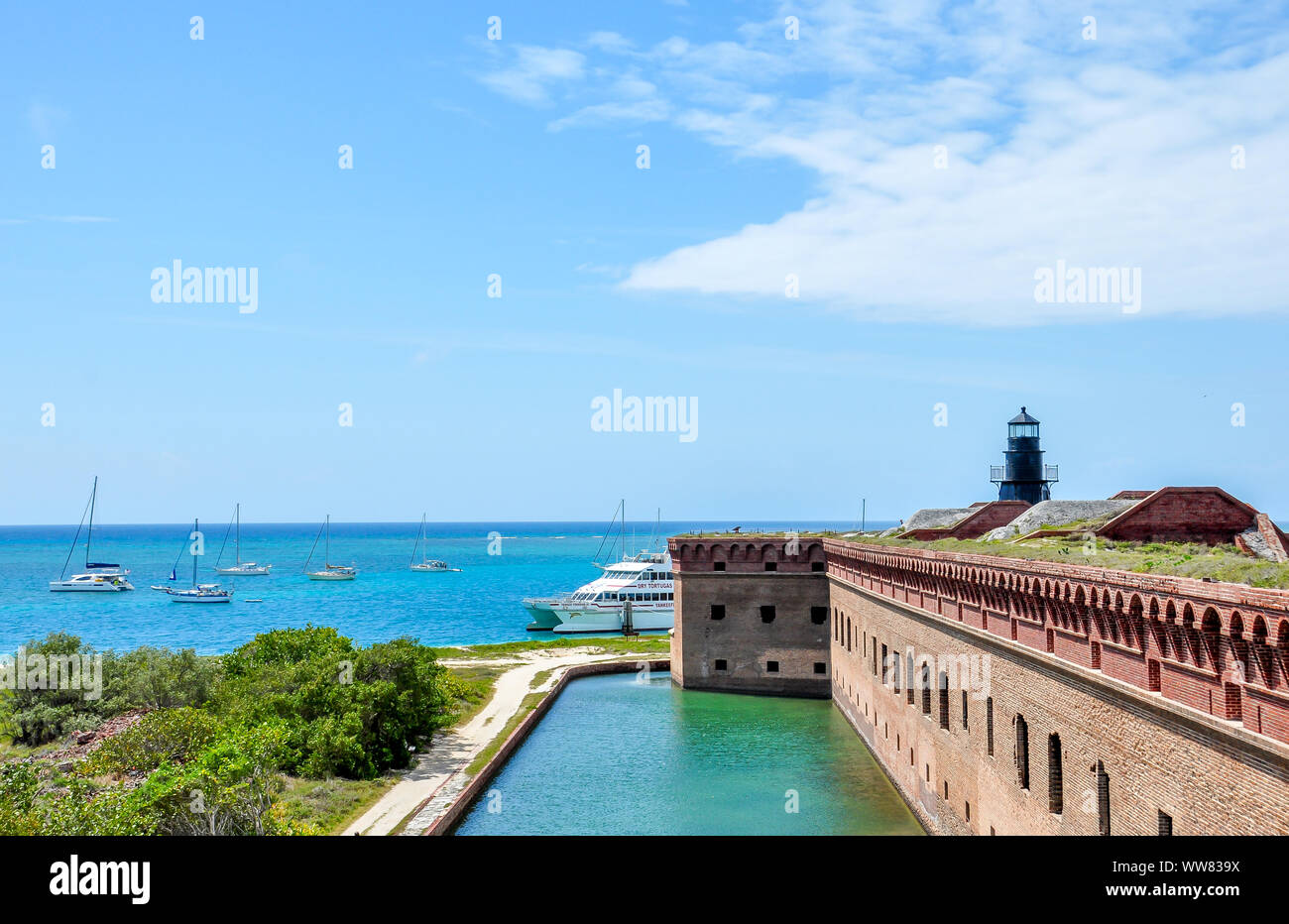 View from Fort Jefferson roof with brick wall, water, sailboats and lighthouse at Dry Tortugas National Park, historic military site, Florida. Stock Photo
