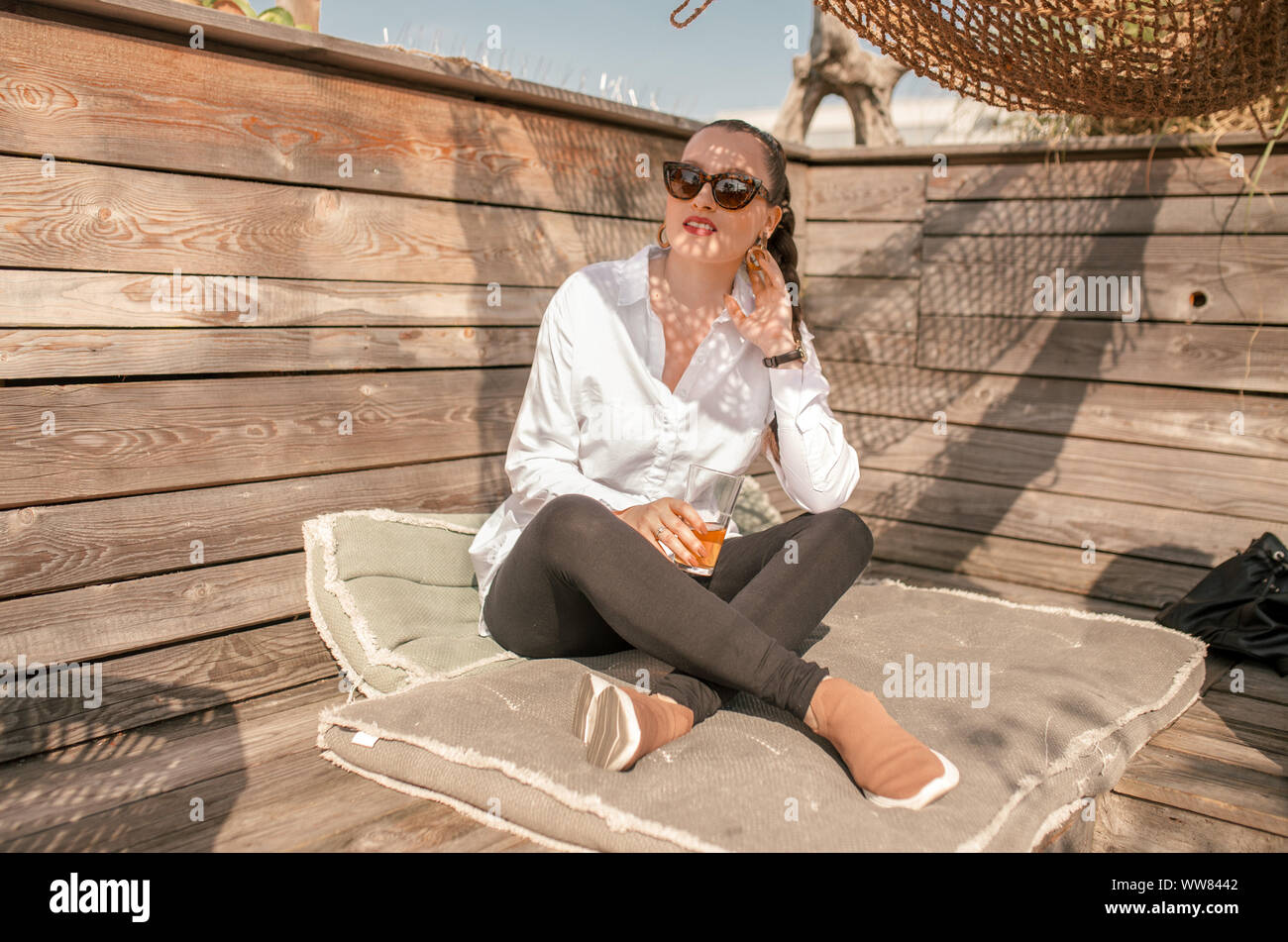 Young woman sitting on pillows at the dachgarten in Munich Stock Photo