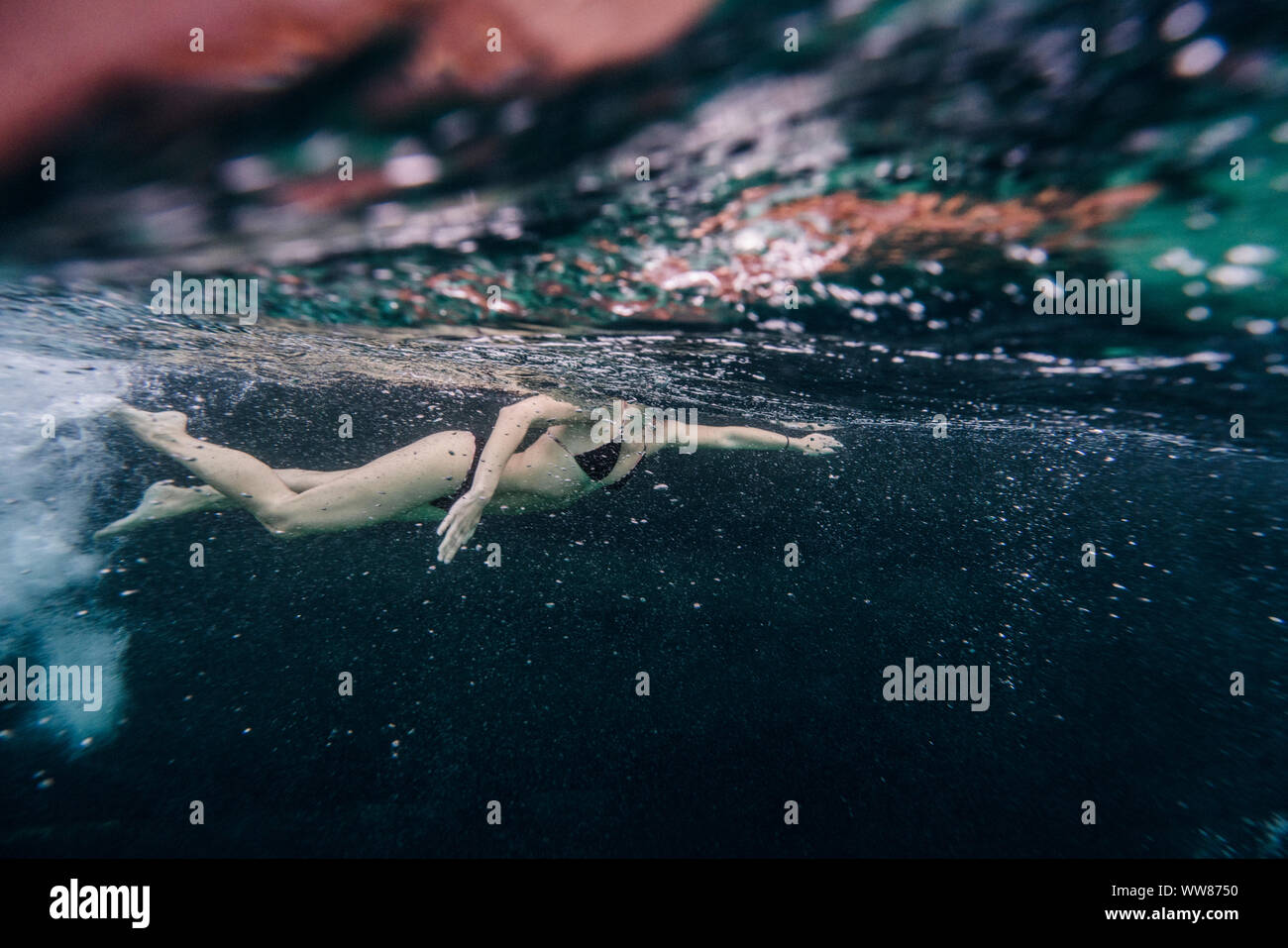 Full length of woman swimming underwater close to an old boat Stock Photo
