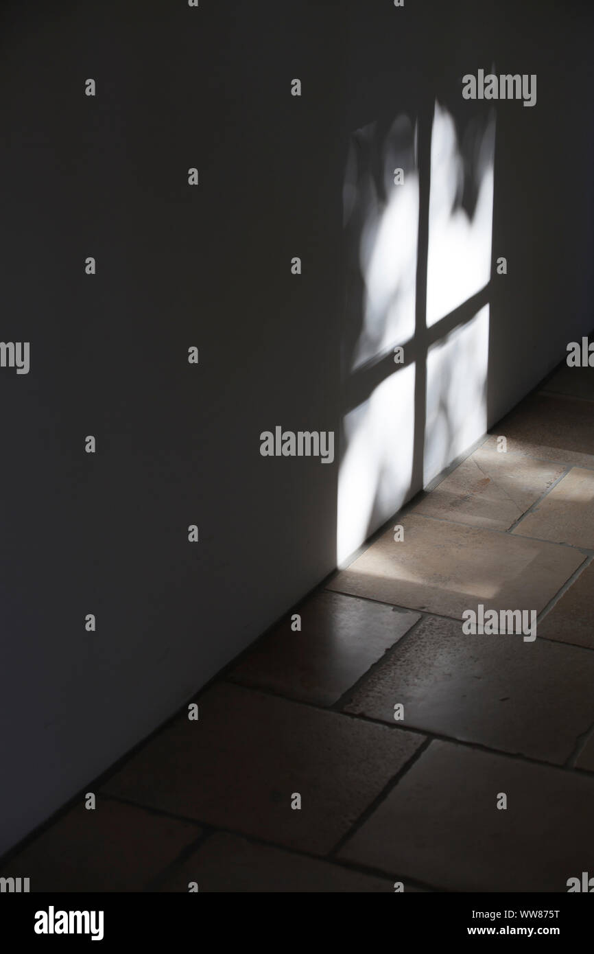 Shadow of window cross on white wall in the house corridor Stock Photo