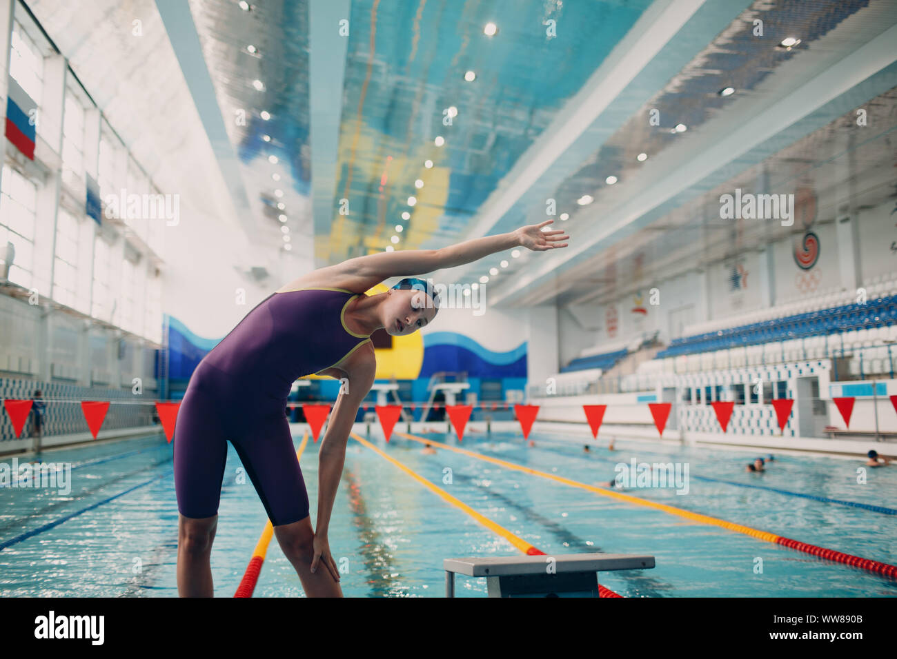 Young woman swimmer warming up before swim in swimming pool Stock Photo