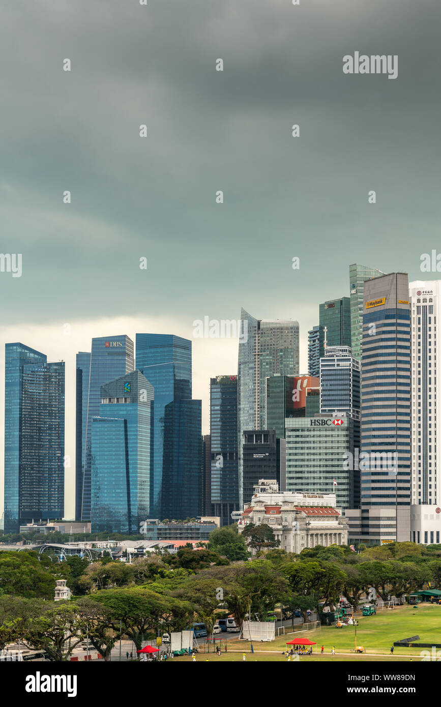 Singapore - March 20, 2019: Partial portrait of financial district skyscrapers from bay to Bank of China under dark gray cloudscape. Part of Padang, f Stock Photo