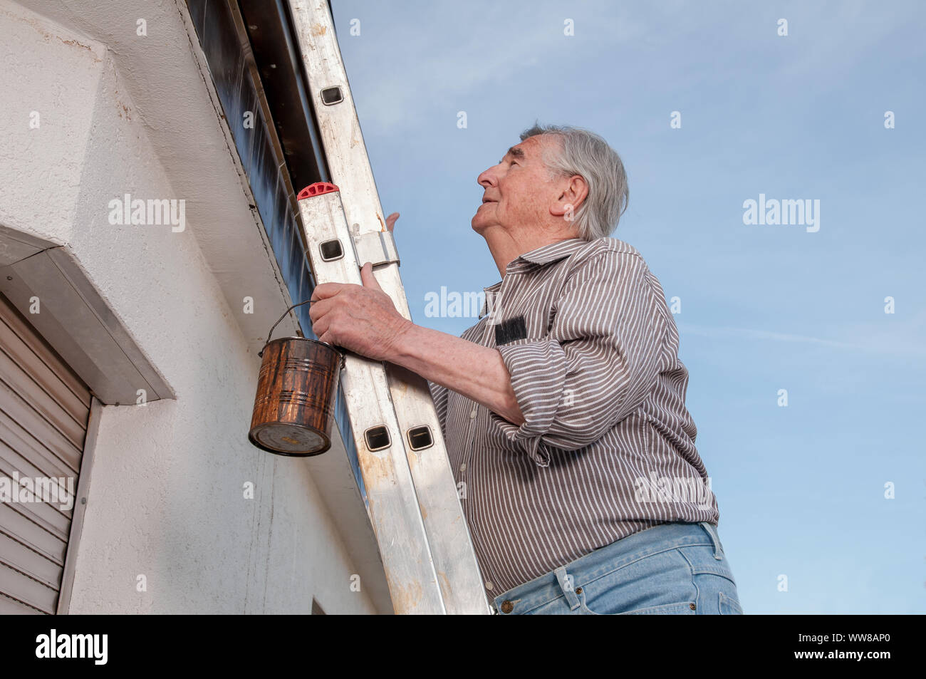 Senior climbing up a dangerous ladder Stock Photo