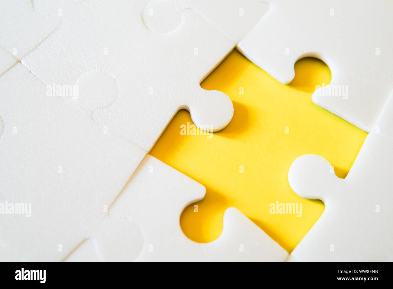 Multiple white puzzle pieces put together without one piece. View from above. Stock Photo