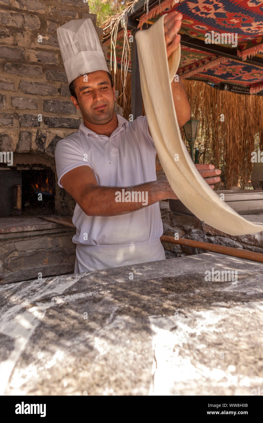 Turkish pide baker baking pide for tourists at an outdoor kitchen at the beach, Near Bodrum, Turkish Riviera, Turkey, Eurasia, Stock Photo