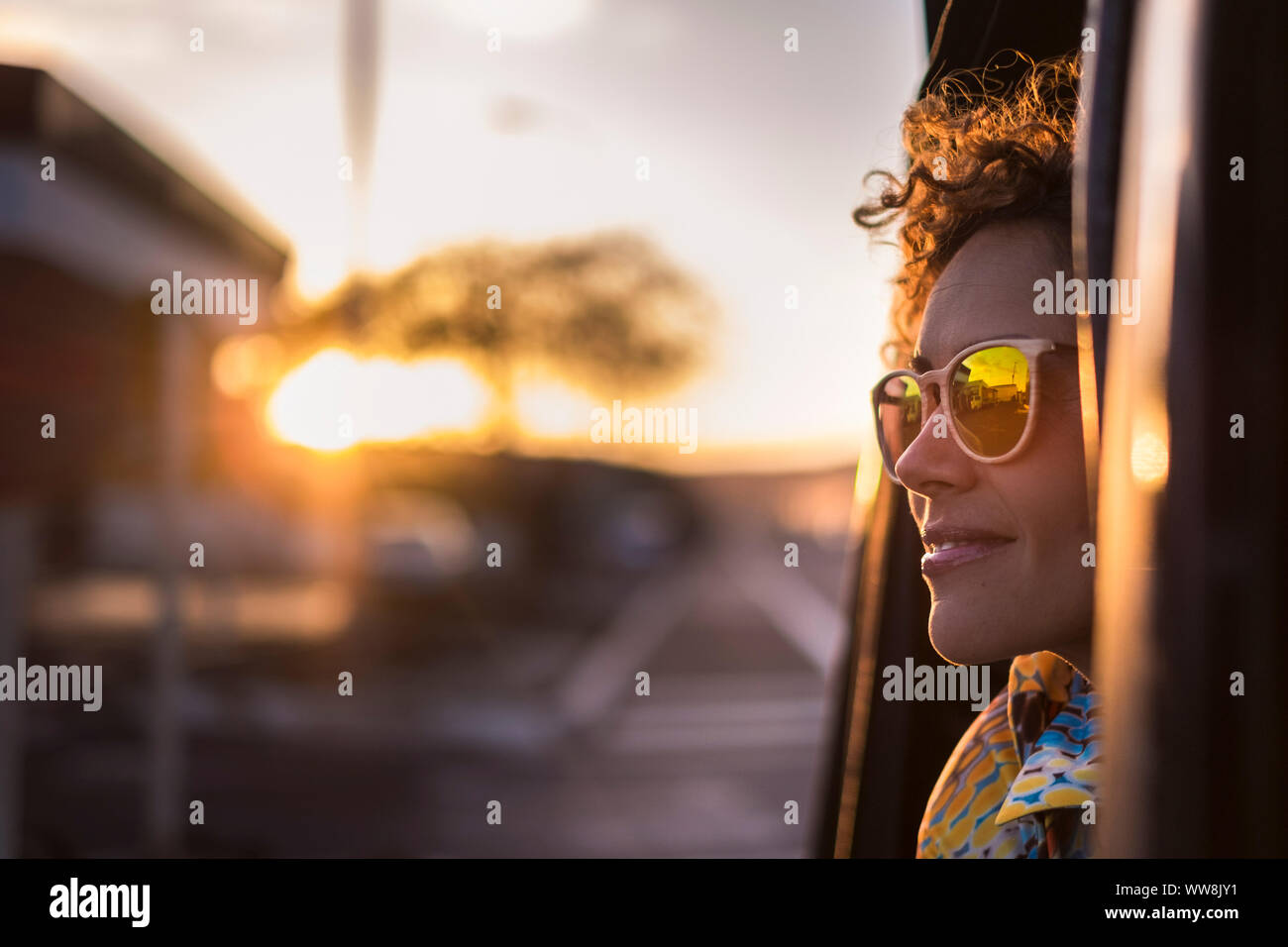 beautiful woman travel on a car looking outside and enjoy the light of the golden sunset on her face. nice lifestyle and peaceful emotions traveling around the world Stock Photo