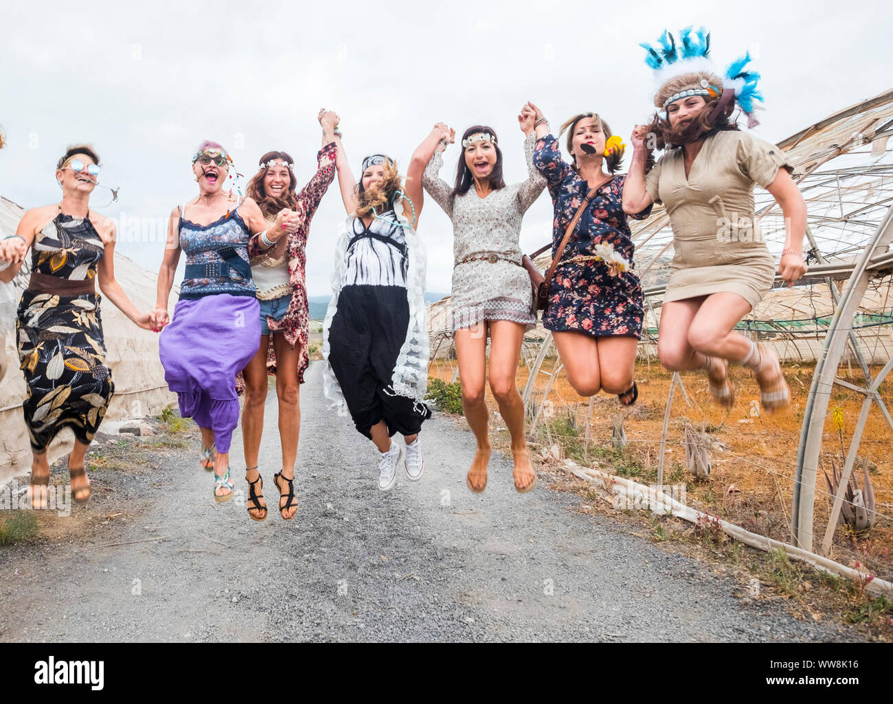 party on with many beautiful females mixed ages from young to middle to old ones everybody jump with joy. hippy and alternative dresses and summer festival concept outside in the countryside Stock Photo