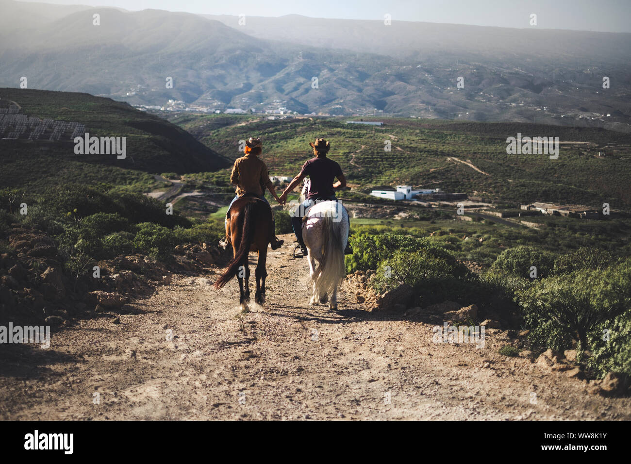couple in love riding two beautiful horses stay together in a travel adventure for alternative lifestyle and vacation. togetherness couple traveling concept to discover the world and the future Stock Photo