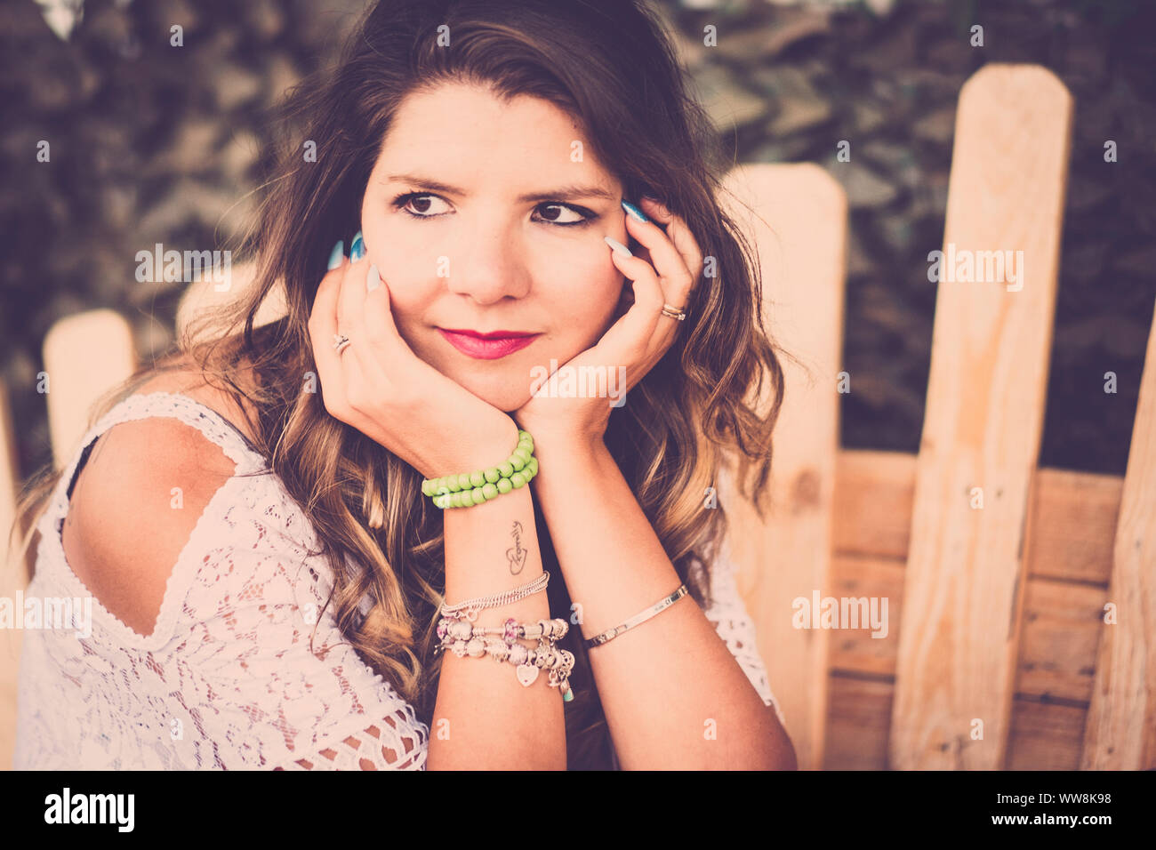 hippy style dress and hair lady like '70s sitting on a wood bench made