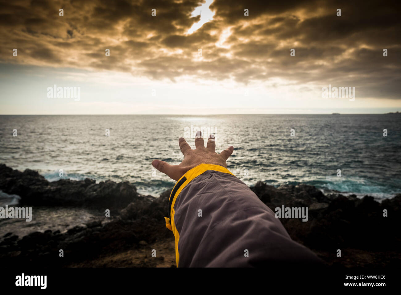 adventure concept for man hand like to touch the horizon. free travel spirit to discover the wild of the world and the beauty of the nature. sunset time and hikers journey at the end Stock Photo