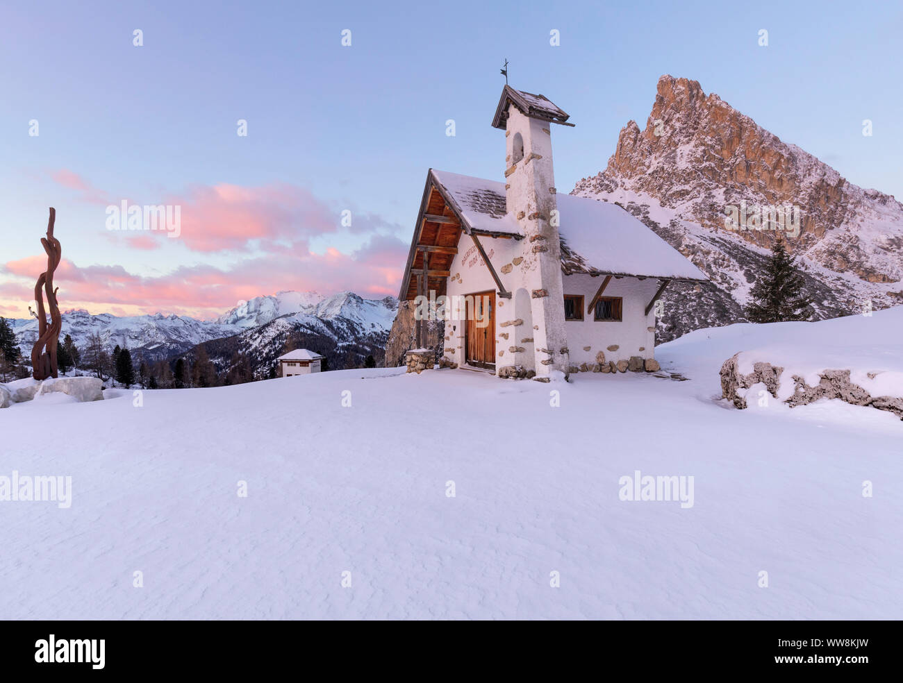 Alpine church of the Visitation in winter with Sass de Stria mount in background, Passo Falzarego, Cortina d'Ampezzo, Dolomites, Belluno, Vento, Italy Stock Photo
