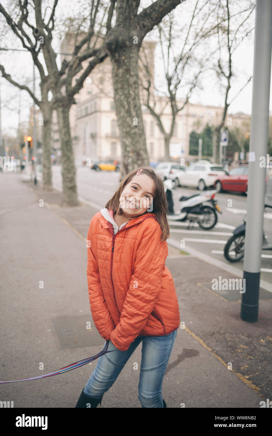 little girl on the streets of barcelona smiling on a winter day with a red jacket Stock Photo