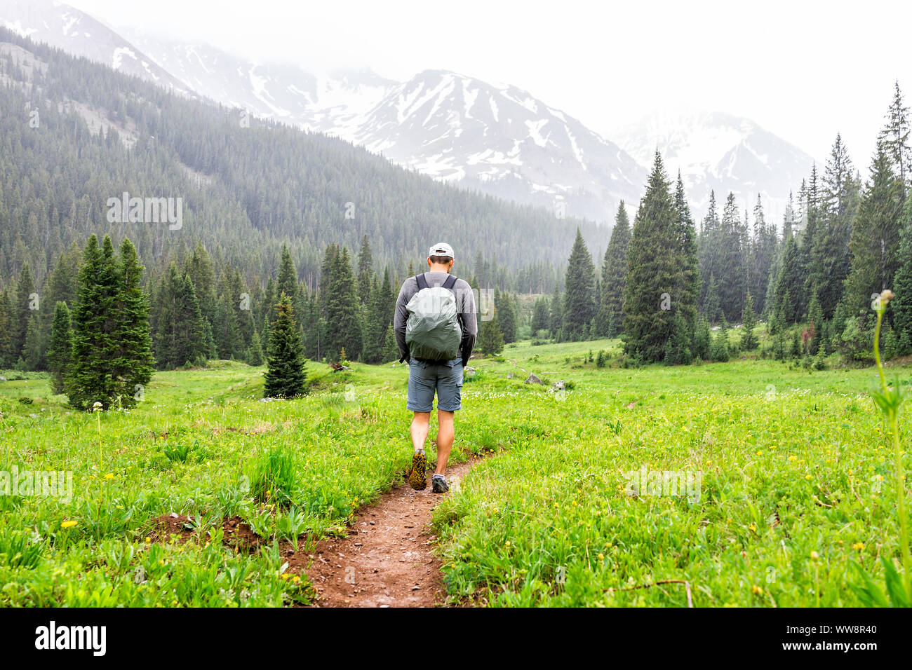Open valley with man walking in rain on Conundrum Creek Trail in Aspen