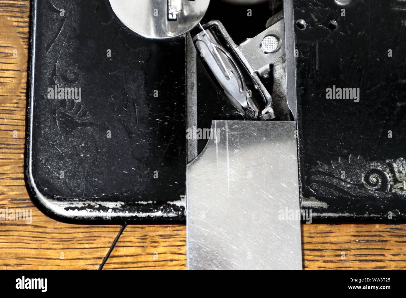 close up of open faceplate on antique sewing machine, showing shuttle, shuttle race, and shuttle holder Stock Photo