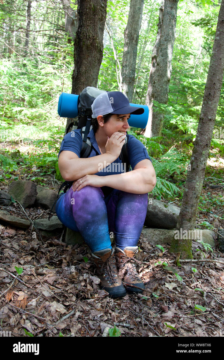 Worried woman has become lost or afraid in the woods while hiking Stock Photo