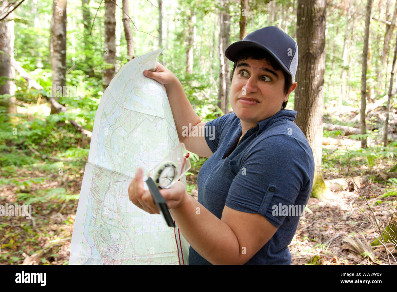 Person with a map and compass is lost in the woods, expression unsure ...