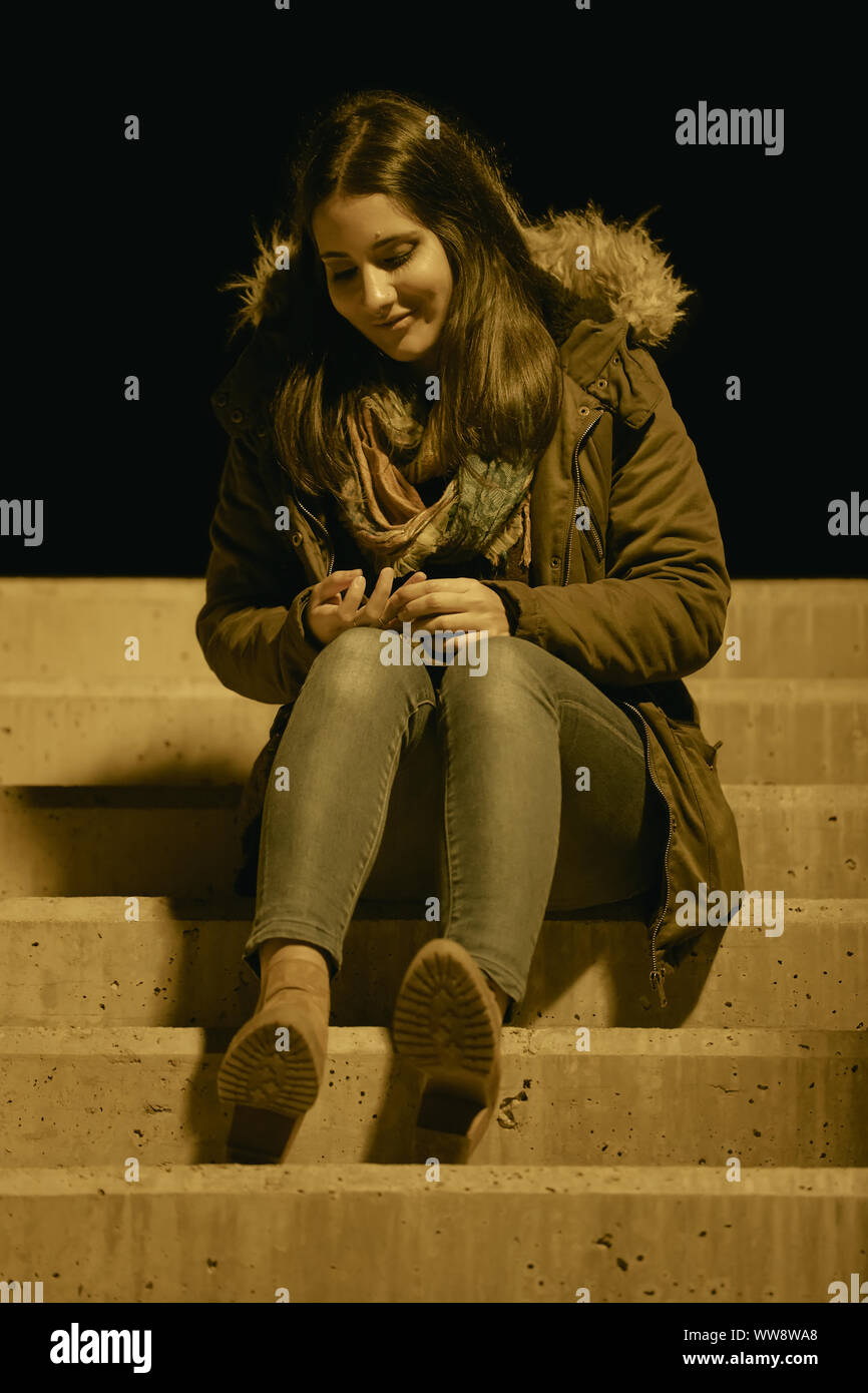 Girl with winter clothes sitting on a stairs at outdoor Stock Photo