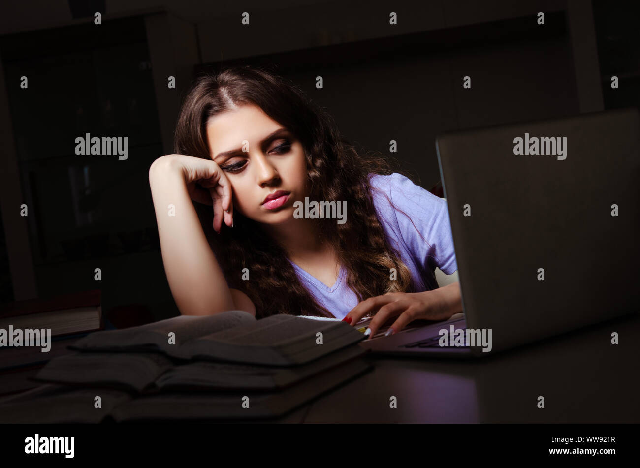 The young female student preparing for exams late at home Stock Photo ...