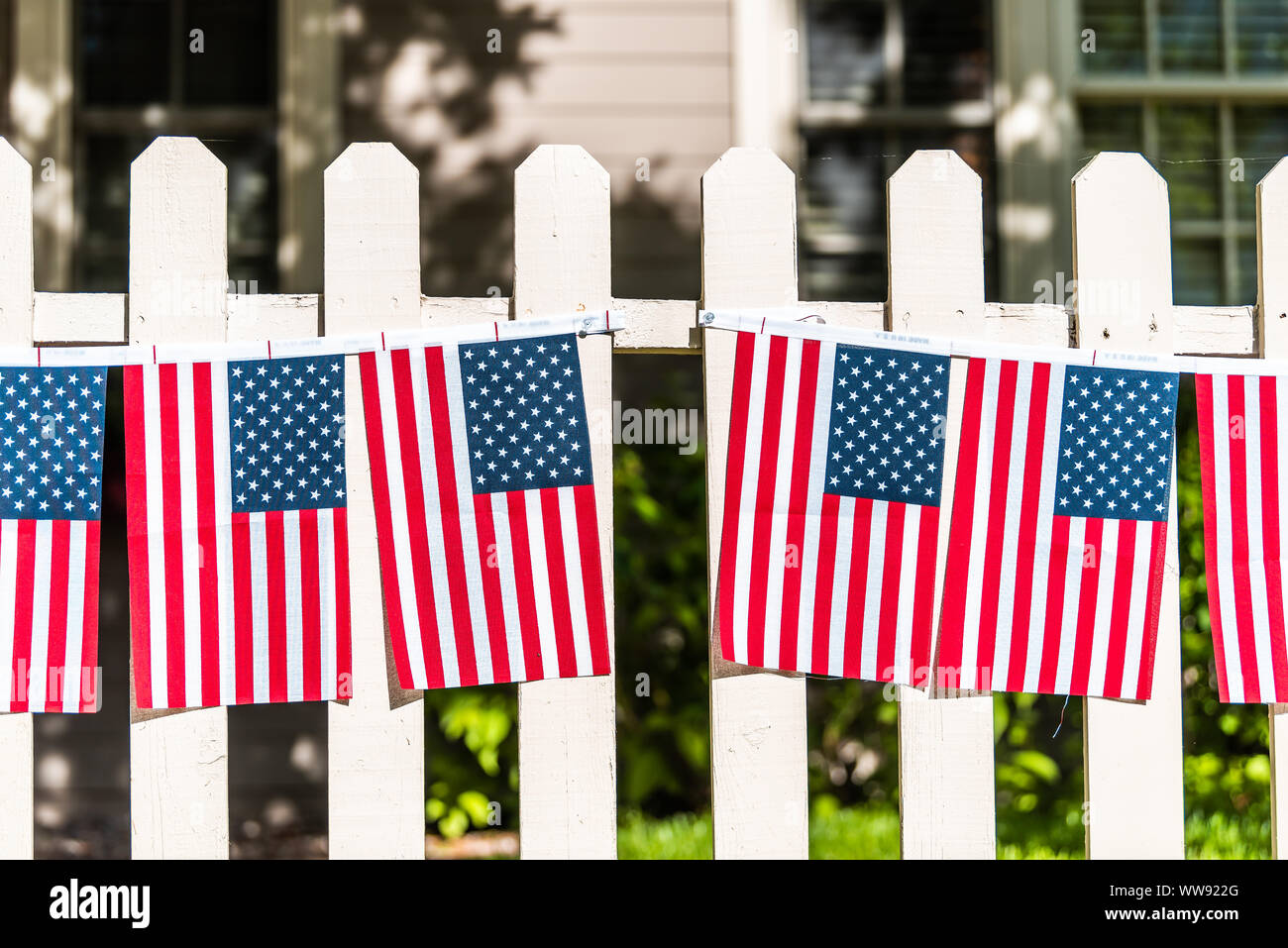 Patriotic American flags hanging decorations on white picket fence in