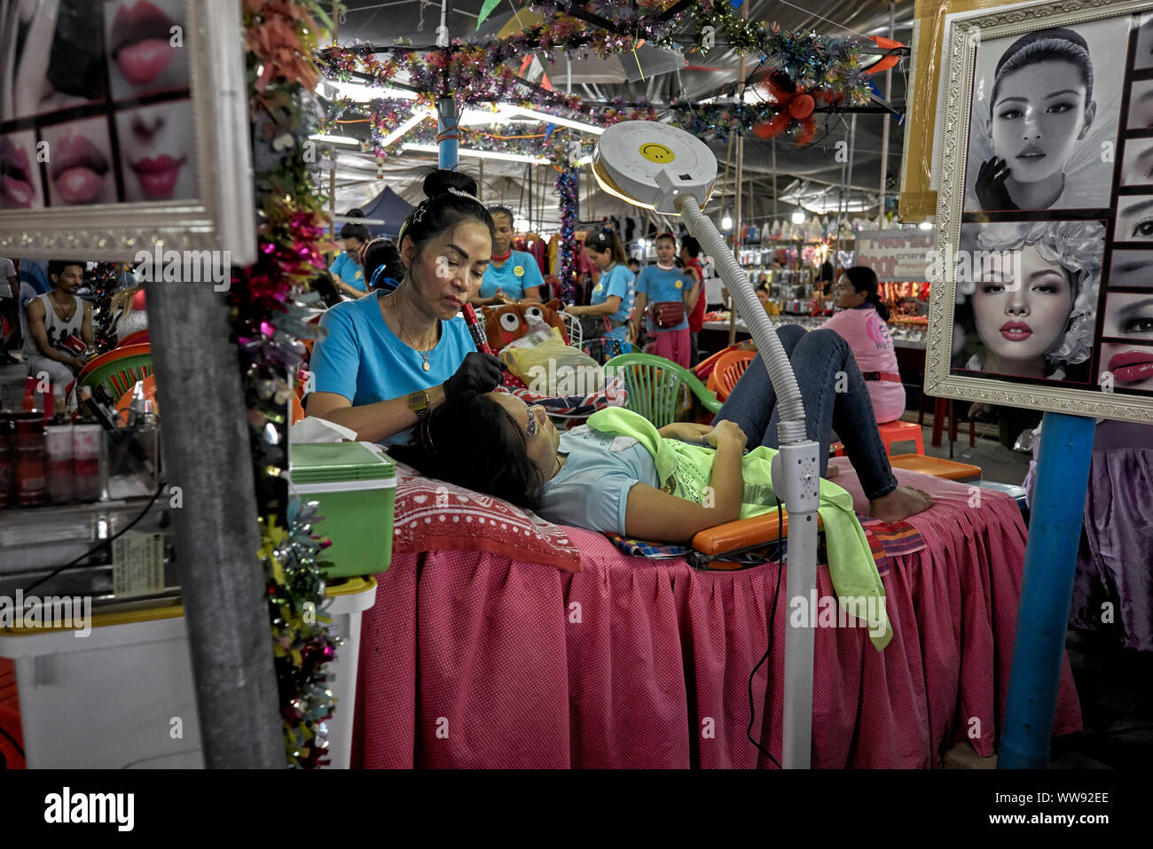 Eyebrow tattoo. Beauty treatment area of a Thailand indoor market with woman getting an eyebrow enhancement tattoo.  Pattaya. Southeast Asia Stock Photo