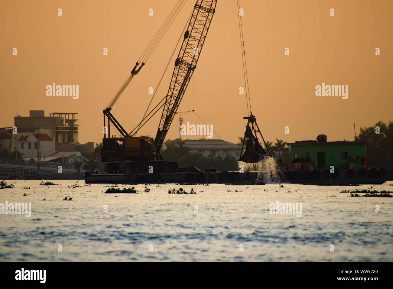 Silhouette of a heavy lift crane taking out something from the river surface of Mekong Delta, Vietnam Stock Photo