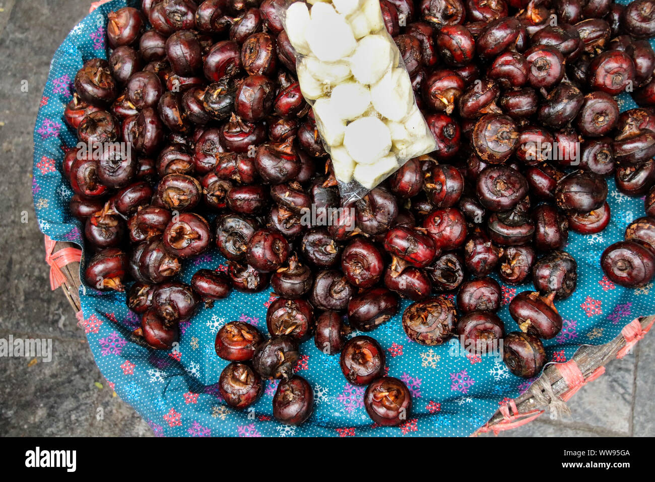 Eleocharis dulcis or water chestnuts sold as popular snack and street food in Hanoi Vietnam, showing authentic candid Vietnamese food and culture Stock Photo