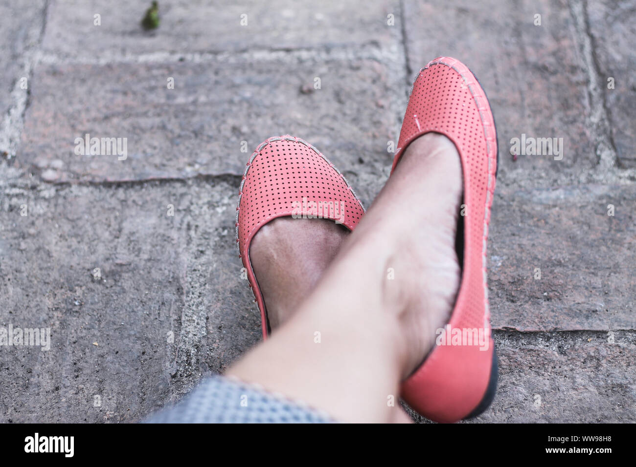 Woman feet wearing pink doll shoes to show concept of how the travel and tourism has nearly stopped due to the covid-19 pandemic Stock Photo