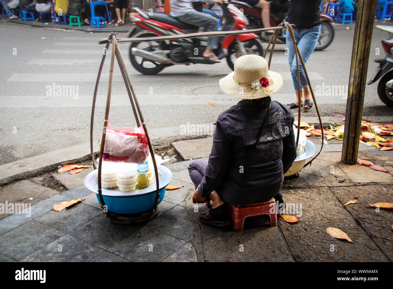 Editorial. A Vietnamese woman selling street food on the side of the busy street in French Quarter Hanoi City, Vietnam Stock Photo