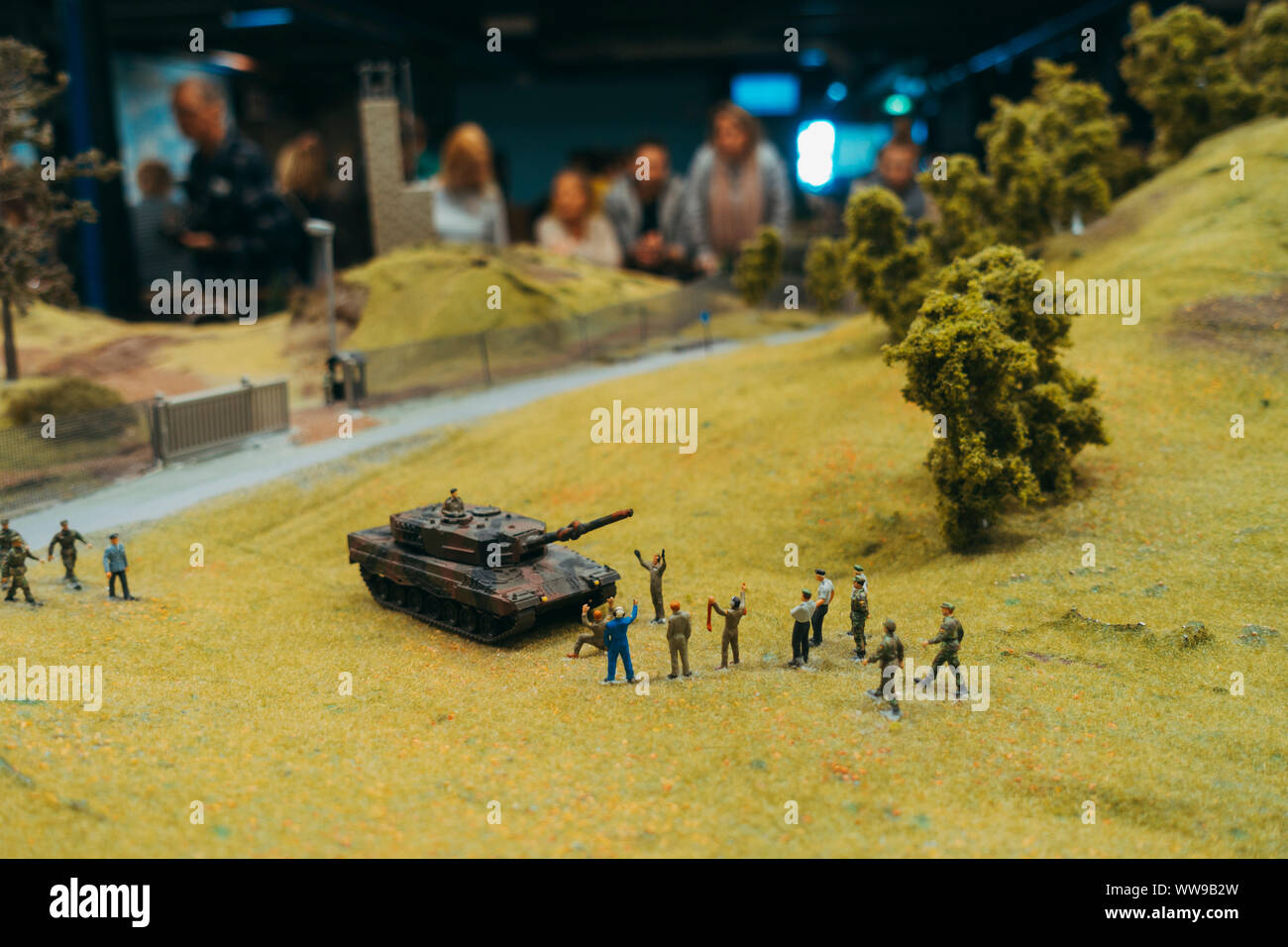 A miniature tank sits on a miniature battlefield whole model troops surrender and visitors look on at Miniatur Wunderland, Hamburg Stock Photo