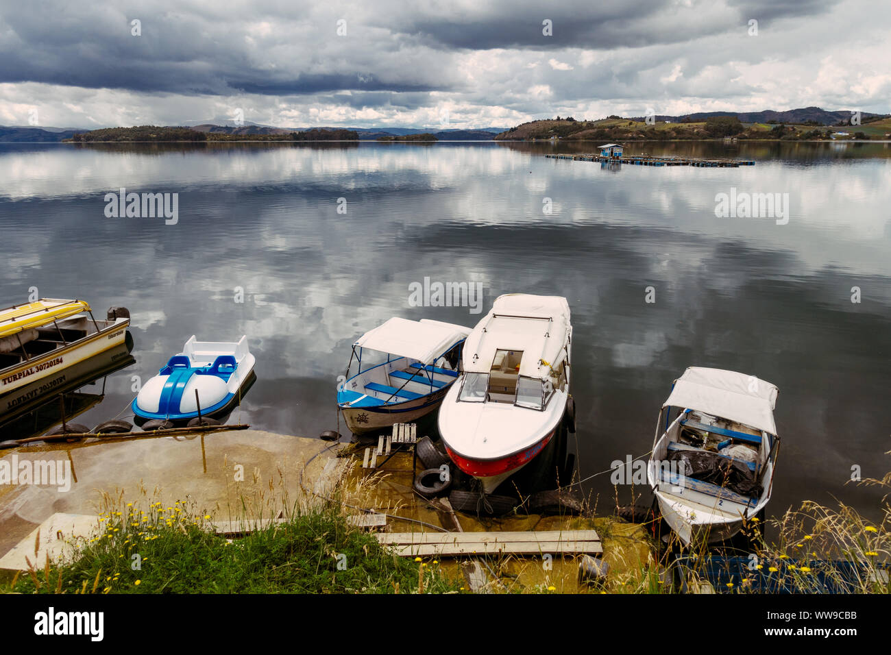 Boats sit on the mirror-like reflective waters of Laguna de Tota, Boyaca, Colombia Stock Photo