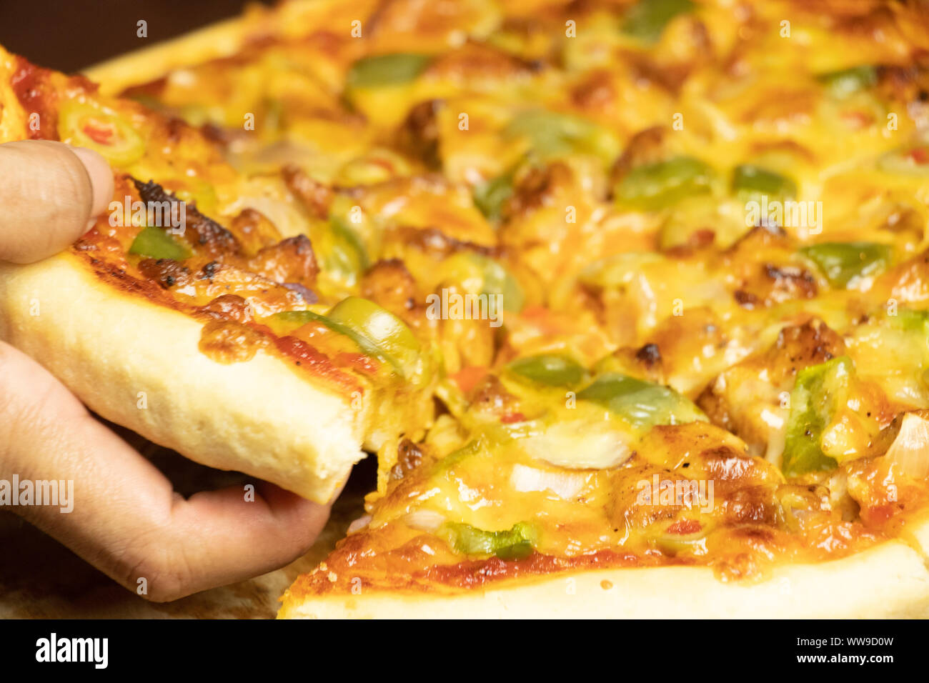 Pan Pizza Slice Take From Hand Side View With Dark Brown Wood Stock Photo Alamy