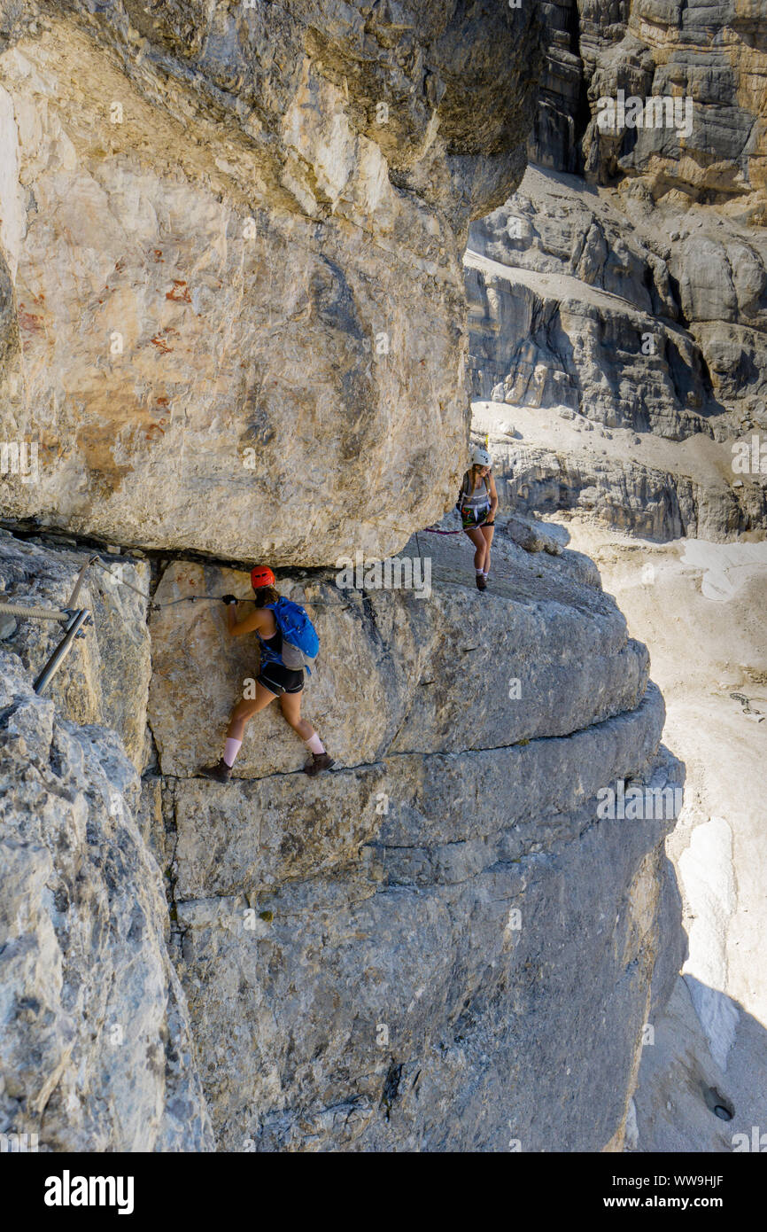 two female mountain climbers on very exposed Via Ferrata in Alta Badia